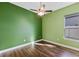 Empty bedroom with green accent wall, wood-look floors, and ceiling fan at 2731 Flintlock Ave, Clermont, FL 34711