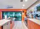 Modern kitchen with orange cabinets, stainless steel appliances, and a farmhouse sink at 6320 Rocky Point Rd, Lake Wales, FL 33898