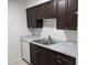 Condo kitchen with dark cabinets, double sink, and granite countertops at 4818 S Semoran Blvd # 508, Orlando, FL 32822