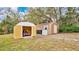 View of two storage sheds, one yellow, one brown, in a backyard setting at 45 Sackett Rd, Debary, FL 32713