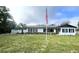 Newly renovated home with white exterior, landscaping, and American flag at 1625 Normandy Way, Leesburg, FL 34748