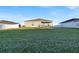 Expansive backyard showcasing a home, grassy lawn, and a white fence at 2325 Crossandra St, Mascotte, FL 34753