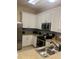 White kitchen with stainless steel appliances, double sink, and tiled backsplash and floor at 605 Rum Run # 605, Davenport, FL 33837