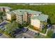 Aerial view showcasing the condo building, parking lot, and surrounding trees at 9051 Treasure Trove Ln # 102, Kissimmee, FL 34747