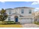 Two-story home with blue front door, attached garage, and landscaped yard at 1528 Mulligan Blvd, Davenport, FL 33896