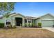 Green one-story home with a two-car garage and landscaped front yard at 5761 Woodruff Way, Lakeland, FL 33812