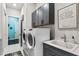 Laundry room with front-loading washer and dryer, gray cabinets, and utility sink at 6535 Shimmering Shores Ln, St Cloud, FL 34771