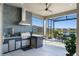 Outdoor kitchen with stainless steel grill, range hood, and screened enclosure overlooking water at 6535 Shimmering Shores Ln, St Cloud, FL 34771