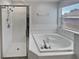 Main bathroom featuring a soaking tub, walk-in shower, and tile flooring and walls at 148 Harwood Cir, Kissimmee, FL 34744