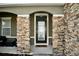 Front entryway with stone accents around door, porch, and glass front door at 1727 Wood Path, Auburndale, FL 33823