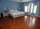 Spacious main bedroom with wood floors, a king-size bed, and arched windows at 915 Ekana Green Ct, Oviedo, FL 32765