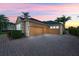 Three-car garage, paver driveway, and stucco exterior at sunset at 715 Sanctuary Dr, Oviedo, FL 32766