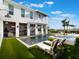 Modern white farmhouse with pool, spa, outdoor kitchen, and lush green lawn at 25 Cunningham Dr, New Smyrna Beach, FL 32168