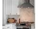 Close-up of the kitchen's stainless steel stove, range hood, and herringbone backsplash at 25 Cunningham Dr, New Smyrna Beach, FL 32168