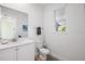 Clean and modern half bathroom with white cabinetry, a single vanity, and a window at 2956 Caribbean Soul Dr, Kissimmee, FL 34747