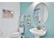 Stylish powder room with pedestal sink, oval mirror, and beach-themed art at 3056 Parrot Head Pl, Kissimmee, FL 34747