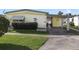 Cute yellow mobile home with carport and landscaped yard at 115 Palm Dr, Eustis, FL 32726