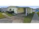 Mobile home with carport, landscaping, and walkway at 115 Palm Dr, Eustis, FL 32726