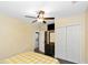 Bedroom with yellow and white checkered bedding, wood floors, and ceiling fan, with view of laundry room at 1413 Dorothy Ave, Haines City, FL 33844