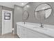 Modern bathroom featuring double sinks, white vanity, round mirrors, and gray walls at 3966 Lake Mira Dr, Orlando, FL 32817