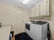 Laundry room with white washer and dryer, overhead cabinets, and folding counter at 707 Coachman Dr, Leesburg, FL 34748