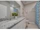 Dual vanity bathroom with granite countertop, white cabinets, and blue shower curtain at 10152 Huntingnet Way, Leesburg, FL 34748