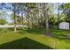 View of the backyard with green grass, trees, and a small storage shed at 1469 Swan Pl, Kissimmee, FL 34759