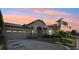 Front exterior of a house with a two-car garage, stone accents, and a landscaped yard at sunset at 2920 Orangebud Dr, Kissimmee, FL 34746