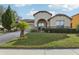 Front exterior of a home with a beige facade, arched entryway, and green lawn at 2920 Orangebud Dr, Kissimmee, FL 34746