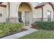 Front entrance of a house with an arched doorway, stone accents, and green shrubs at 2920 Orangebud Dr, Kissimmee, FL 34746