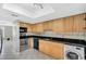 Kitchen with stainless steel appliances, light wood cabinetry, black countertops, and tile floors at 6030 Village Cir, Orlando, FL 32822