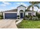 Charming single-story home with a dark blue garage door and lush landscaping at 2213 Grantham Ave, Davenport, FL 33837