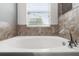 Relaxing soaking tub with tile surround and window view at 2213 Grantham Ave, Davenport, FL 33837