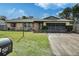 Tan one-story house with a screened-in garage and well-maintained lawn at 1561 Ohara St, Deltona, FL 32725