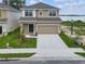 Two-story home with a two-car garage, landscaped yard, and view of a lake at 3013 Tackle Dr, Leesburg, FL 34748