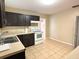 Kitchen with dark cabinets, white appliances, and tile floor at 5165 Gwynne Ave, Orlando, FL 32810