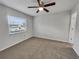 Empty bedroom with neutral gray walls, plush carpeting, and a ceiling fan with windows at 7008 Watseka Ave, Orlando, FL 32818