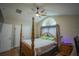 Main bedroom with wooden post bed, hardwood floors, and large window at 8100 Fan Palm Way, Kissimmee, FL 34747
