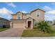 Tan two-story home with red front door, brick driveway, and green lawn at 9401 La Salle St, Groveland, FL 34736