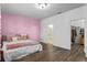 Pink bedroom with a king-size bed, laminated plank flooring, an ensuite bathroom, and walk-in closet at 2833 Hilltop Loop, Apopka, FL 32712