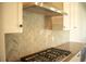 Gas cooktop with herringbone backsplash in modern kitchen at 7493 Estuary Lake Loop, Kissimmee, FL 34747