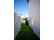 Narrow side yard with grassy lawn and white fence at 7493 Estuary Lake Loop, Kissimmee, FL 34747