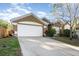 Tan house with white garage door and landscaped yard at 1314 Megan Way, Apopka, FL 32703