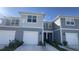 Two-story townhome with gray siding, white garage doors, and landscaping at 2774 Bright Bird Ln, Winter Park, FL 32792