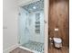 Modern bathroom with glass shower, pebble tile flooring, and a toilet at 10230 Park Ridge Gotha Rd, Windermere, FL 34786
