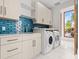 Laundry room with white cabinets and blue tile backsplash at 10230 Park Ridge Gotha Rd, Windermere, FL 34786