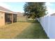View of the backyard with a large tree and white vinyl fence at 428 Palastro Ave, Auburndale, FL 33823