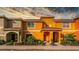 Two-story townhome with orange and green exterior, landscaping, and a walkway at 8931 Bismarck Palm Rd, Kissimmee, FL 34747