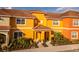 Two-story townhome with orange exterior and landscaping at 8931 Bismarck Palm Rd, Kissimmee, FL 34747