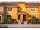 Two-story townhome with orange exterior and landscaping at 8931 Bismarck Palm Rd, Kissimmee, FL 34747